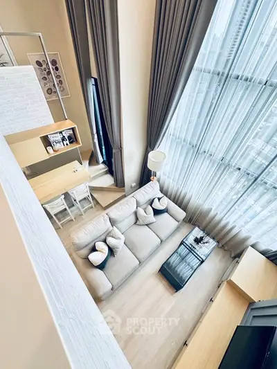 Stunning high-ceiling living room with modern decor and large windows offering city views.