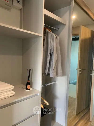 Modern closet with hanging clothes and shelves in stylish apartment