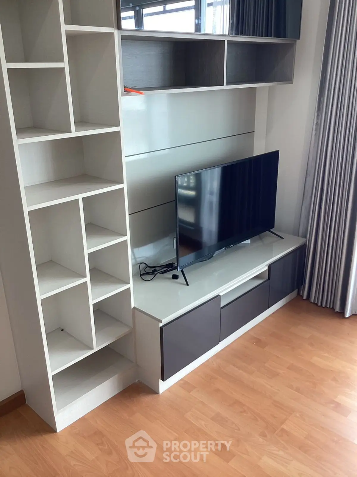Modern living room with sleek TV stand and built-in shelving on wooden flooring.