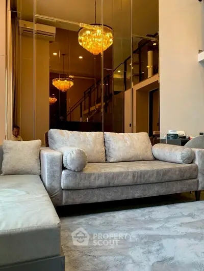 Luxurious living room with plush sofa and elegant chandeliers in modern duplex apartment.