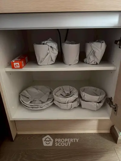 Organized kitchen cabinet with neatly wrapped dishes and baking soda box on wooden shelves.