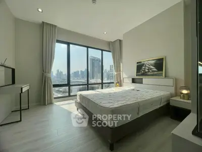Modern bedroom with large windows offering stunning city skyline views, featuring minimalist decor and natural light.