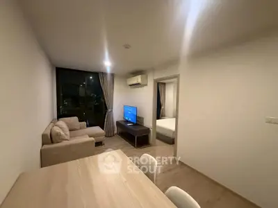 Modern living room with cozy sofa and TV, open to a bedroom, ideal for urban living.