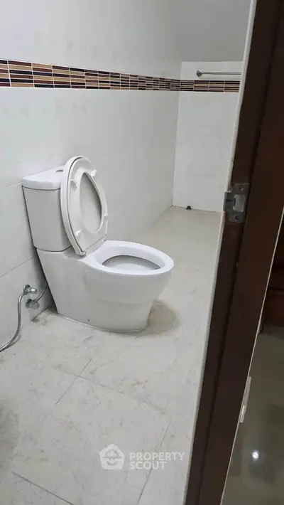 Spacious bathroom with modern toilet and tiled flooring, ideal for comfort and convenience.