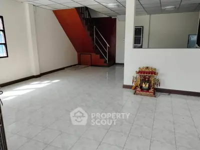 Spacious interior with tiled flooring and staircase, ideal for customization.