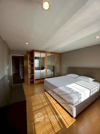 Spacious bedroom with wooden flooring and ample natural light