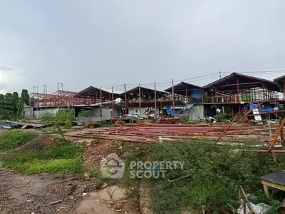 Construction site with steel framework and unfinished buildings under cloudy sky.