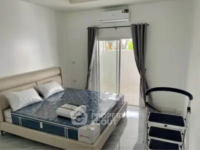 Modern bedroom with new mattress and air conditioning, featuring sliding glass doors to a private outdoor area.
