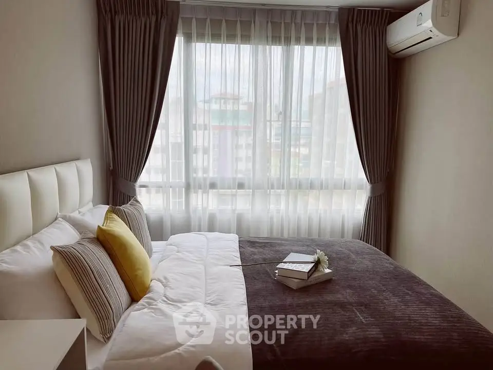 Cozy bedroom with modern decor and large window offering natural light.