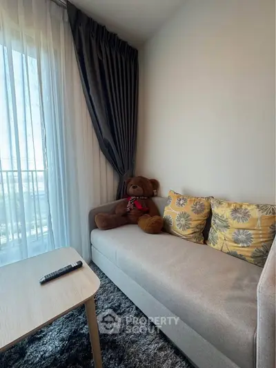 Cozy living room with plush sofa, decorative pillows, and large window with curtains.