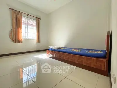 Spacious bedroom with single bed and large window offering natural light.