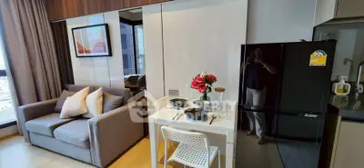 Modern living room with cozy sofa, dining table, and sleek kitchen area in stylish apartment.