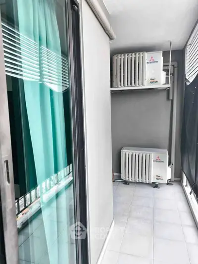 Modern balcony with air conditioning units and sleek glass doors in urban apartment.
