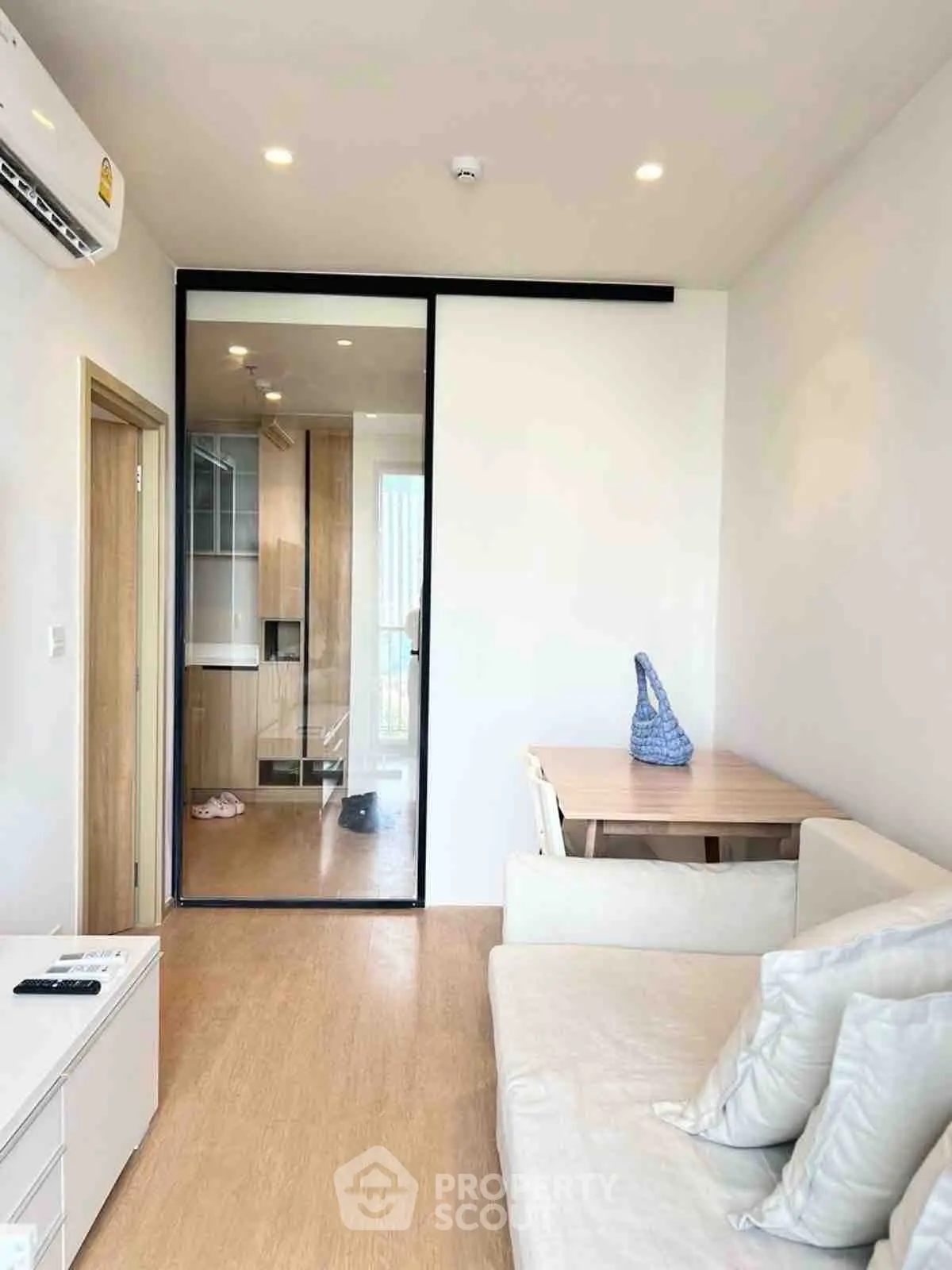 Modern living room with sleek glass partition and cozy seating area.