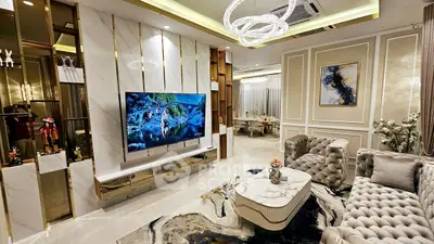 Luxurious living room with elegant decor and modern lighting, featuring plush seating and a large TV.