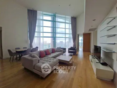 Spacious modern living room with floor-to-ceiling windows and city view.
