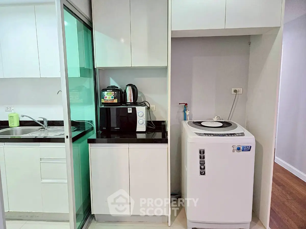 Modern kitchen with washing machine and sleek appliances in compact layout