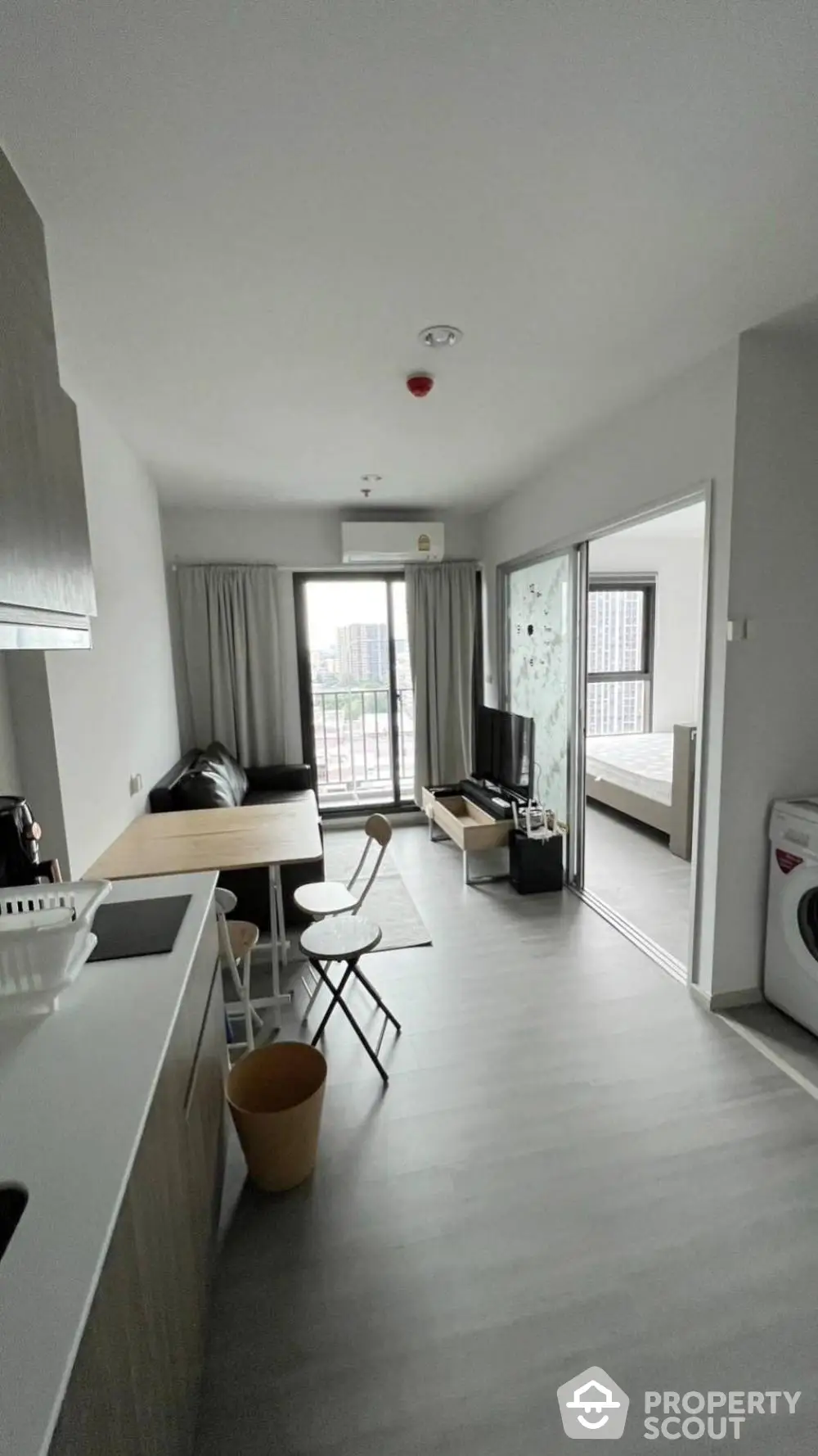 Modern open-plan living room with kitchen and balcony view in a stylish apartment.