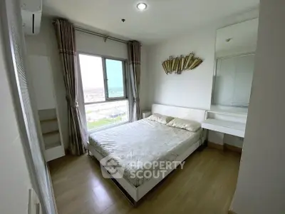 Cozy bedroom with large window and modern decor in a high-rise apartment.