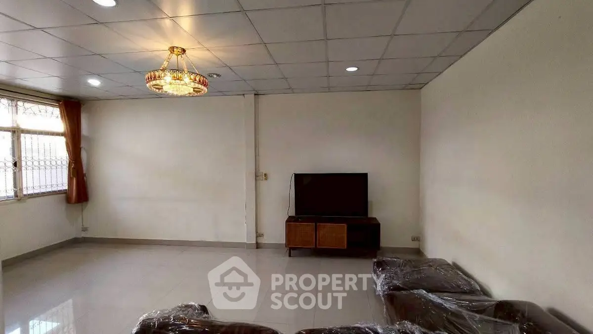 Spacious living room with modern chandelier and large window for natural light.