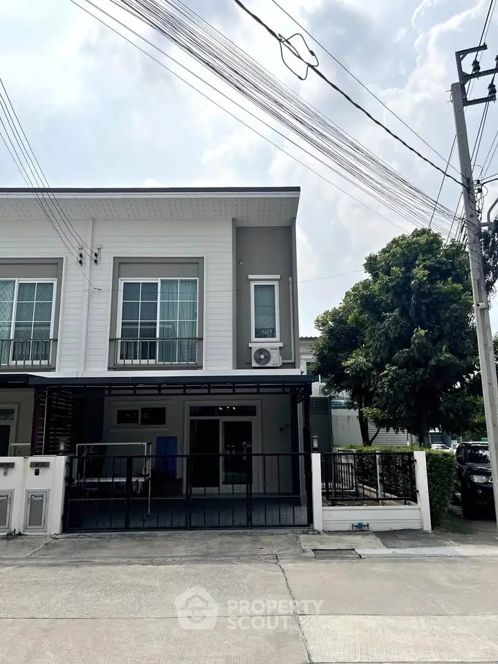 Modern townhouse exterior with large windows and gated entrance in a suburban neighborhood.