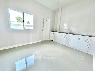 Spacious modern kitchen with sleek white cabinets and large window for natural light.