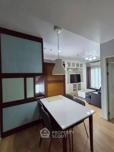 Modern living room with dining area, featuring sleek furniture and stylish lighting.