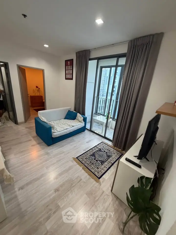 Modern living room with balcony access and stylish decor in a high-rise apartment.