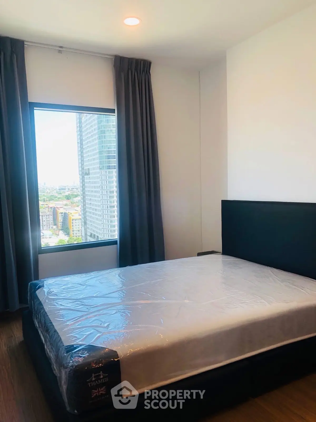 Modern bedroom with large window offering city view in high-rise apartment