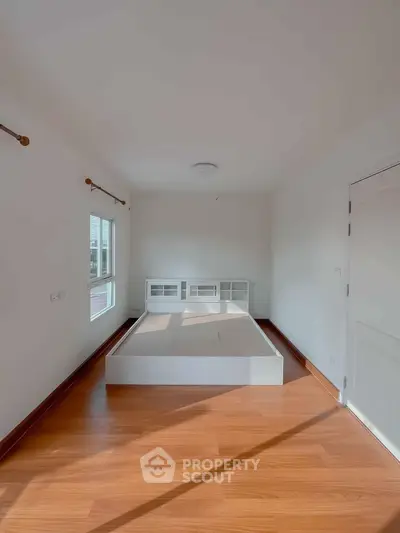 Spacious bedroom with wooden flooring and ample natural light