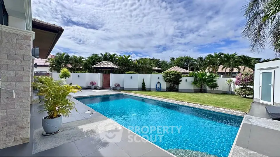 Luxurious outdoor pool area with lush landscaping and clear blue skies, perfect for relaxation and entertainment.