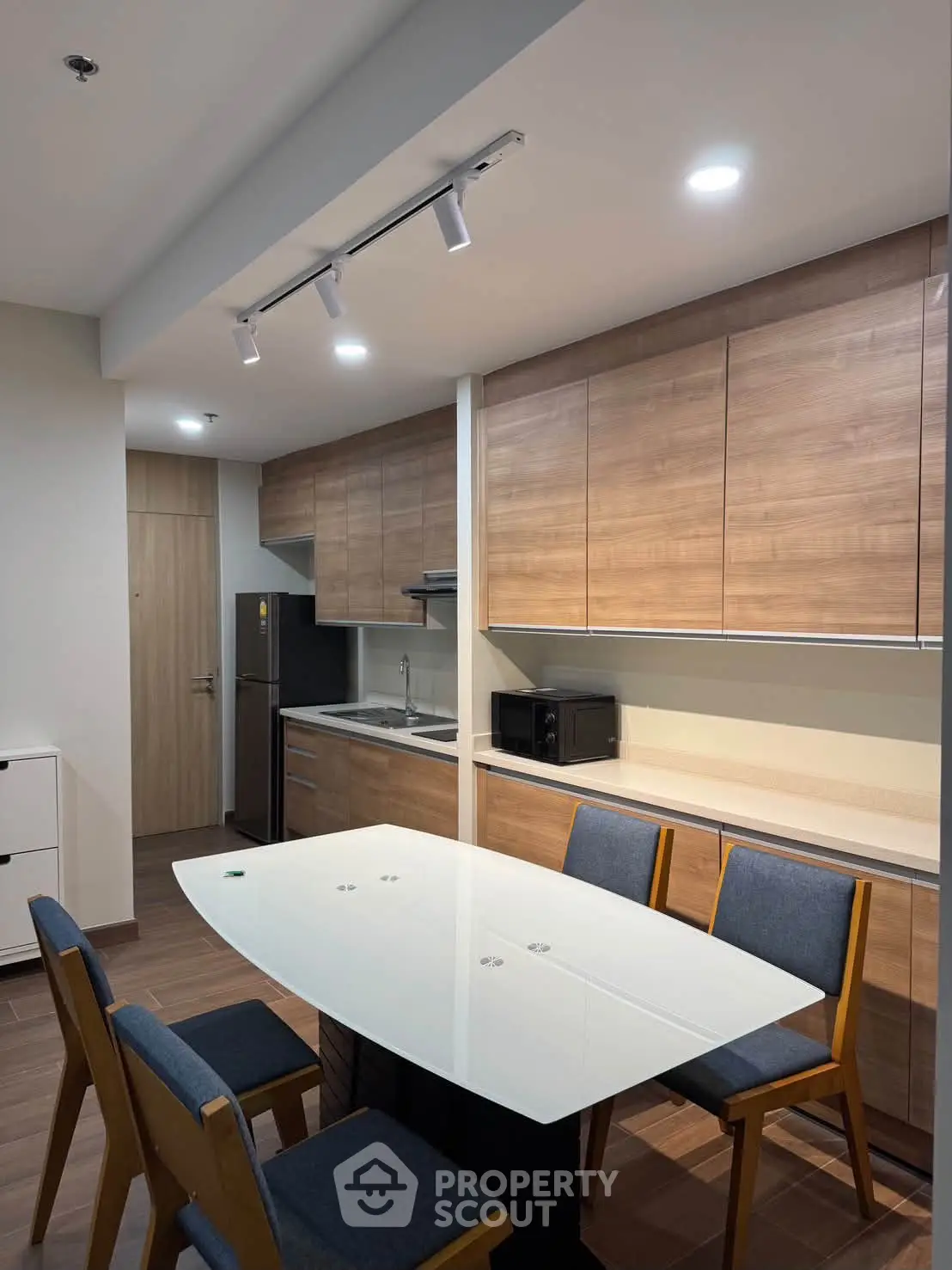 Modern kitchen with sleek wooden cabinets and dining area in contemporary apartment