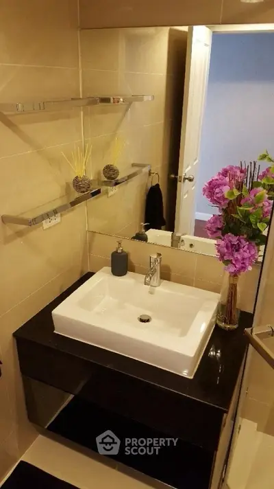 Modern bathroom with sleek sink, elegant mirror, and decorative flowers for a stylish touch.