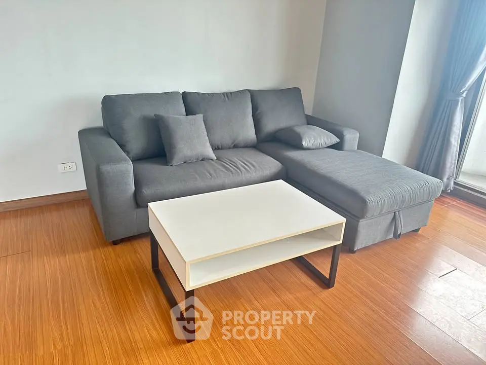 Modern living room with stylish gray sofa and sleek white coffee table on wooden flooring.