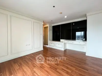 Spacious empty room with elegant wood flooring and built-in storage