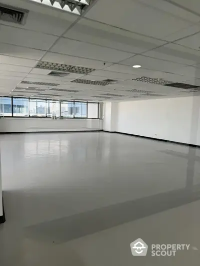 Expansive open-plan commercial space with abundant natural light, ideal for a bespoke office layout, featuring a reflective polished floor and drop ceiling.