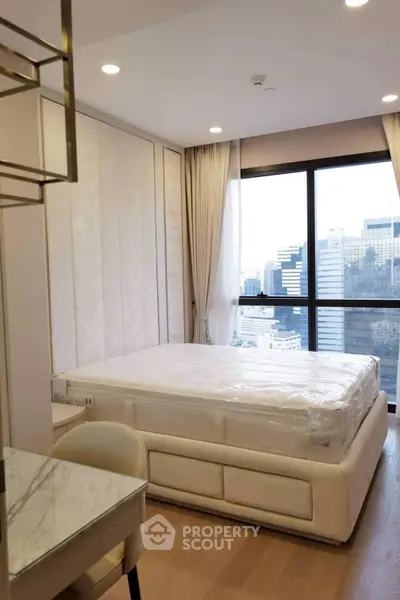 Modern bedroom with large window offering city view, featuring elegant decor and comfortable furnishings.
