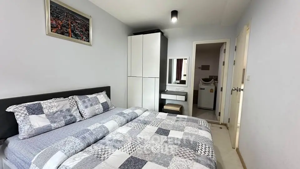 Cozy bedroom with modern decor and convenient ensuite laundry area.