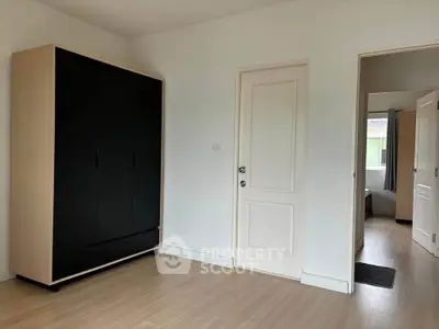 Minimalist bedroom with sleek black wardrobe and wooden flooring
