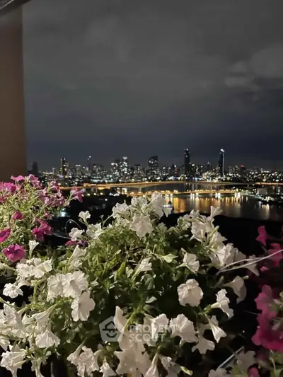 Stunning city skyline view from a balcony with vibrant flowers at night.
