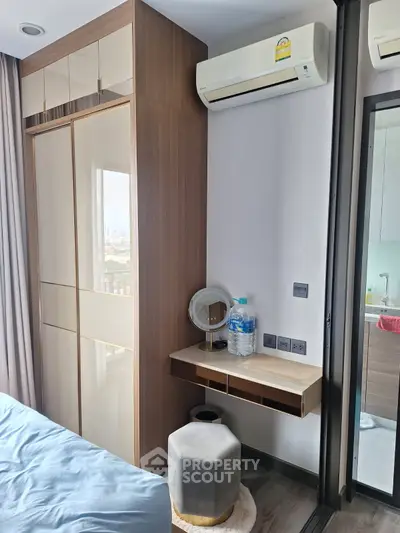 Modern bedroom with built-in wardrobe and air conditioning, featuring a stylish vanity area and city view.