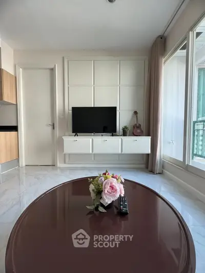 Modern living room with TV, stylish decor, and large windows for natural light.