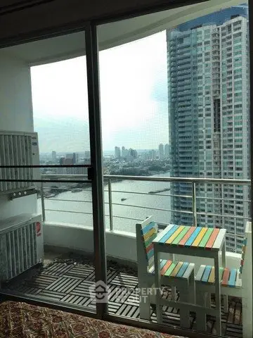 Stunning high-rise balcony with river view and colorful outdoor furniture.