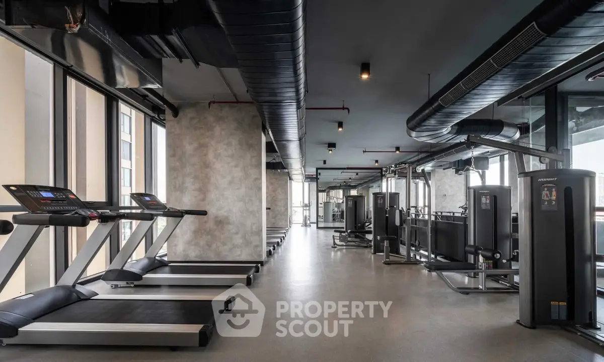 Modern gym with state-of-the-art equipment and large windows in a luxury residential building.