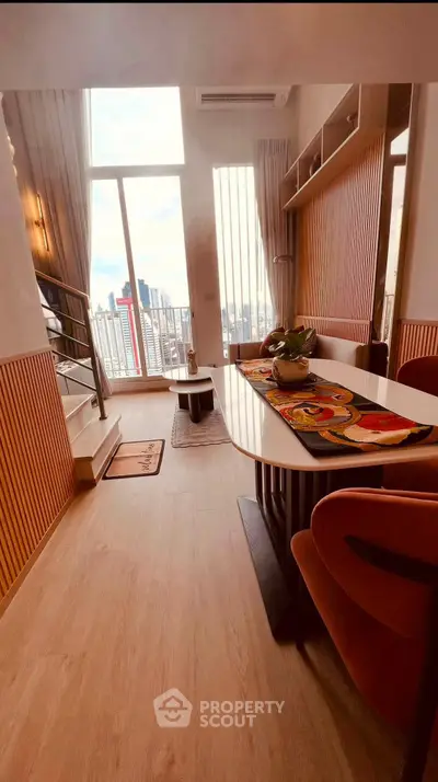 Stylish modern living room with large windows and city view, featuring elegant decor and cozy seating area.