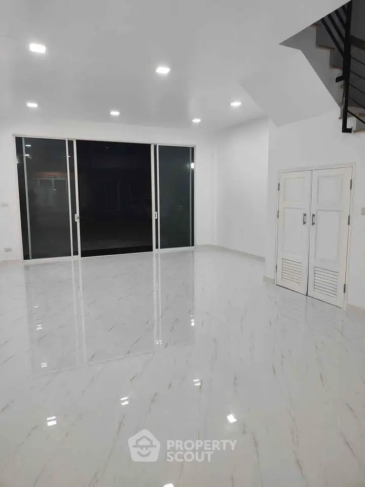 Spacious modern living room with sleek marble flooring and large sliding glass doors.