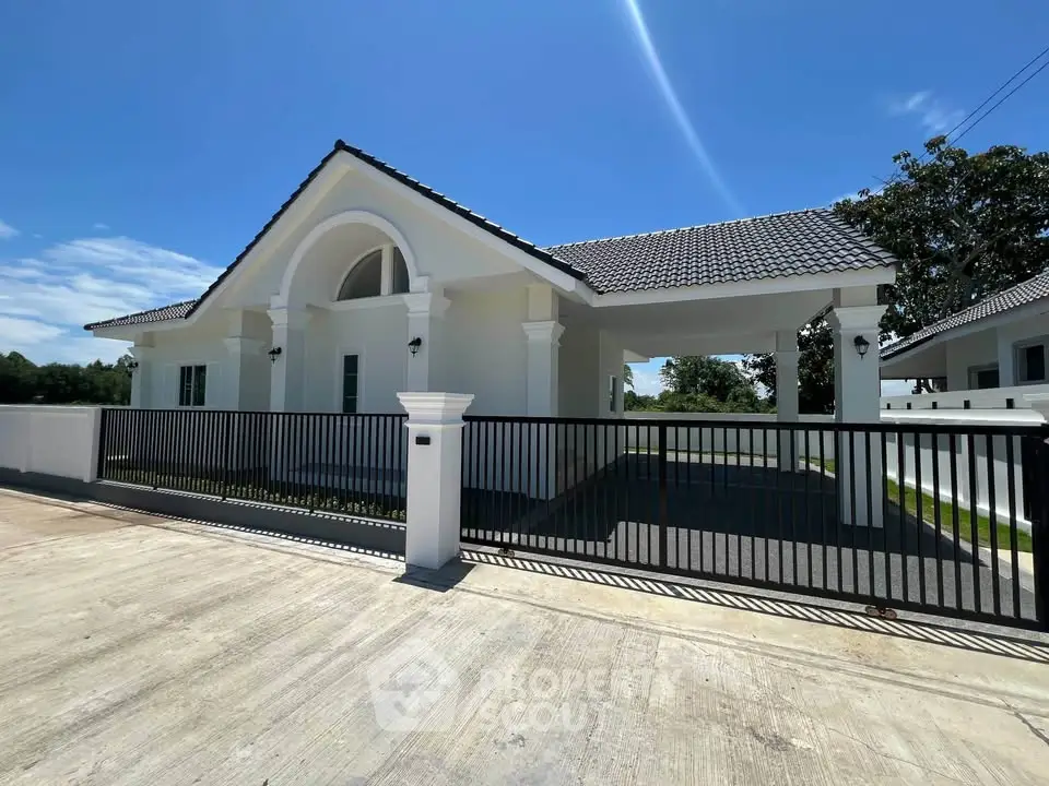 Charming single-story white house with modern design and spacious driveway under clear blue sky.