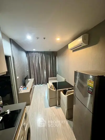 Modern living room with open kitchen, featuring sleek appliances and stylish decor.