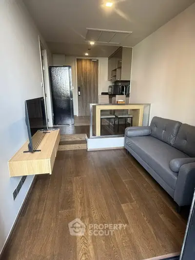 Modern living room with sleek design and open kitchen layout, featuring hardwood floors and contemporary furniture.