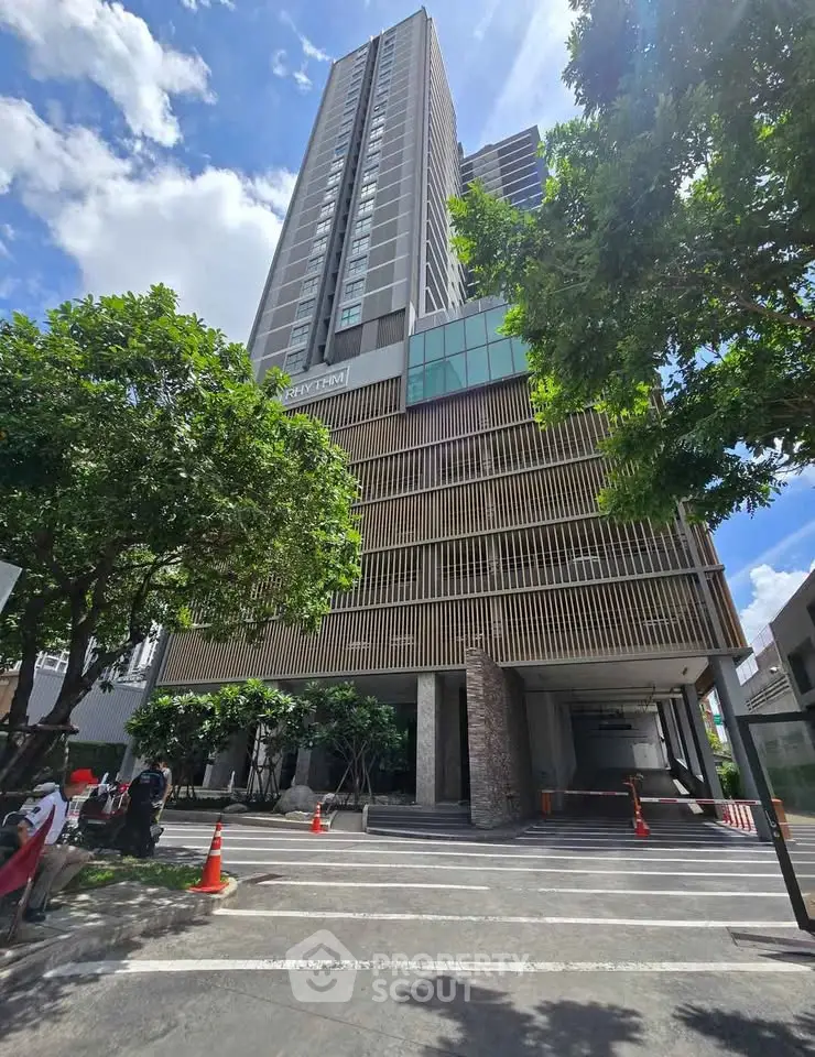 Modern high-rise building with lush greenery and clear blue sky, showcasing urban living at its finest.